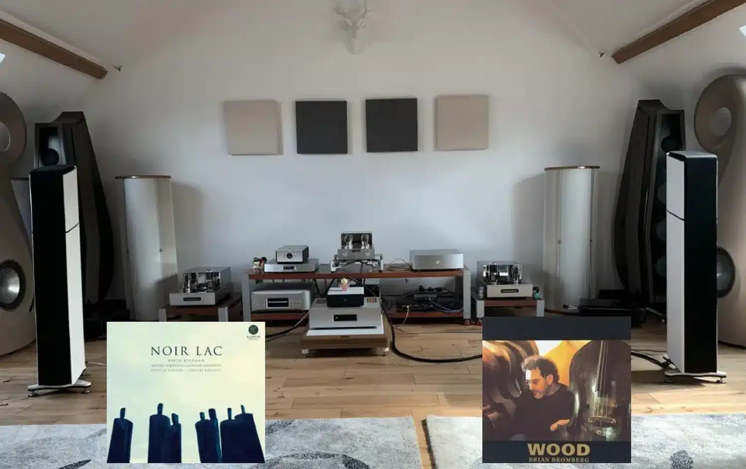 Une salle audio audiophile moderne avec diverses enceintes dont les Æquo Audio Stilla haut de gamme, une décoration minimaliste et deux pochettes d'album exposées au premier plan (par 1877.audio)