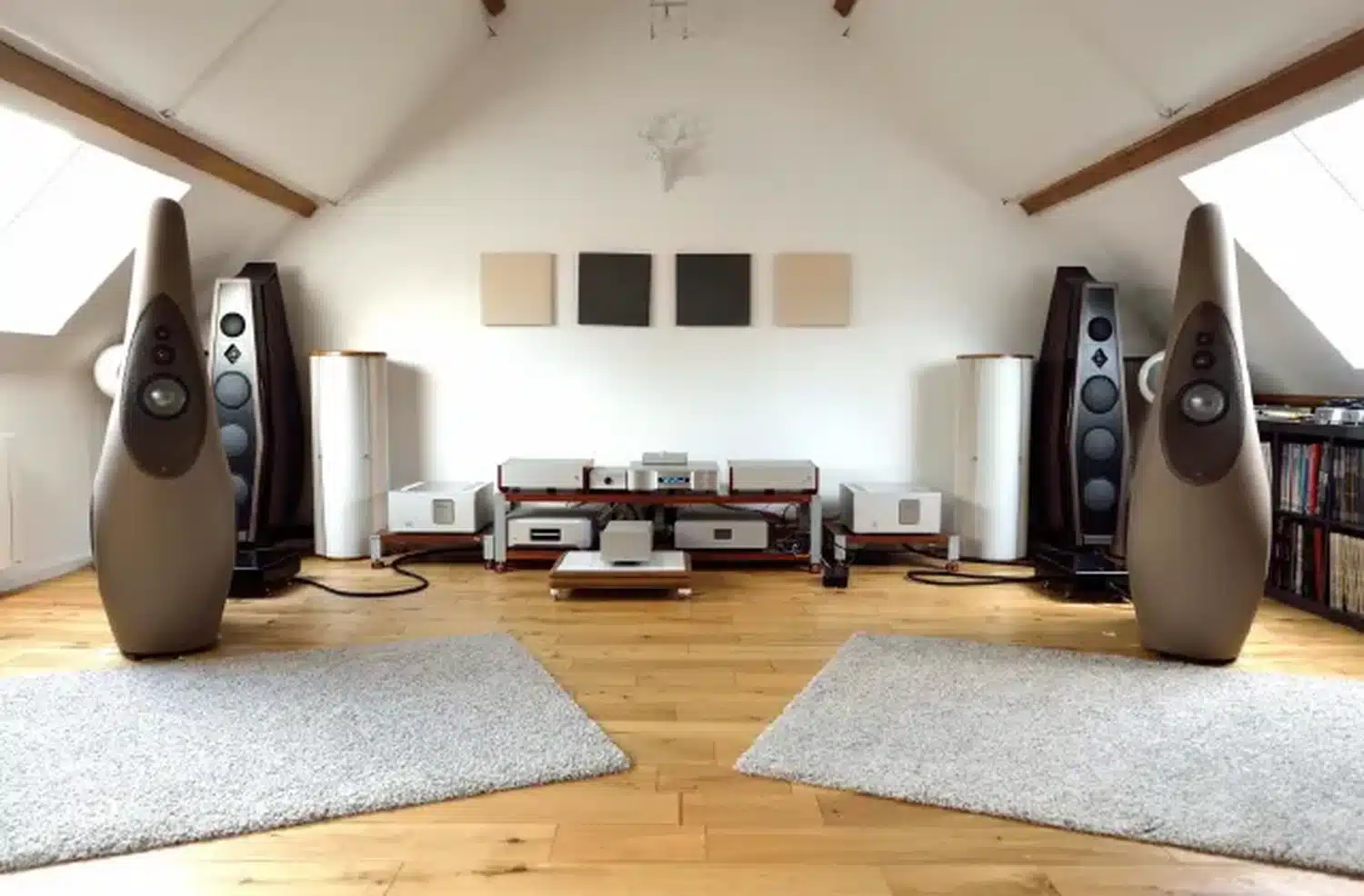 Équipement audio haut de gamme dans une pièce mansardée, comprenant une paire d'enceintes Vivid Audio G1 et le DAC Vermeer Audio Two à l'essai. Au sol des tapis à poils longs sur un plancher en bois clair (par 1877.audio)
