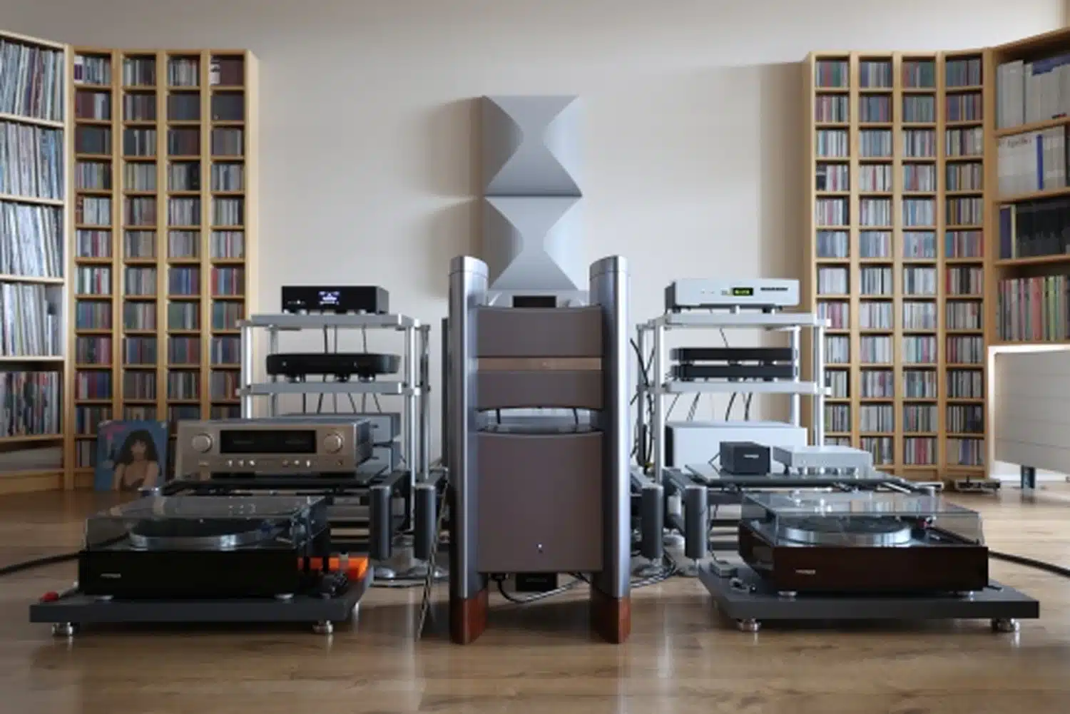 Une salle audio haut de gamme comprenant plusieurs systèmes audio dont l'amplificateur Halcrp Eclipse stéréo, des platines vinyle et avec de grandes étagères de disques vinyles et de CD (par 1877.audio)