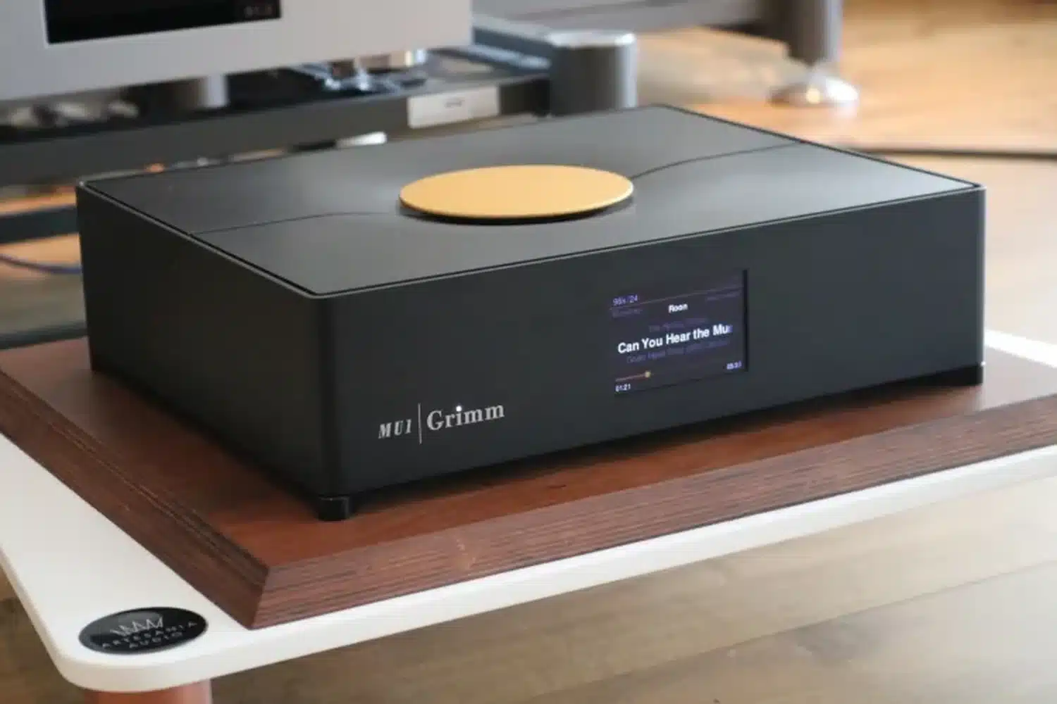 Le Grimm Audio MU1, streamer haut de gamme, affichant le titre de la chanson "Can You ear the music" sur son écran, posé sur un support audiophile (par 1877.audio)