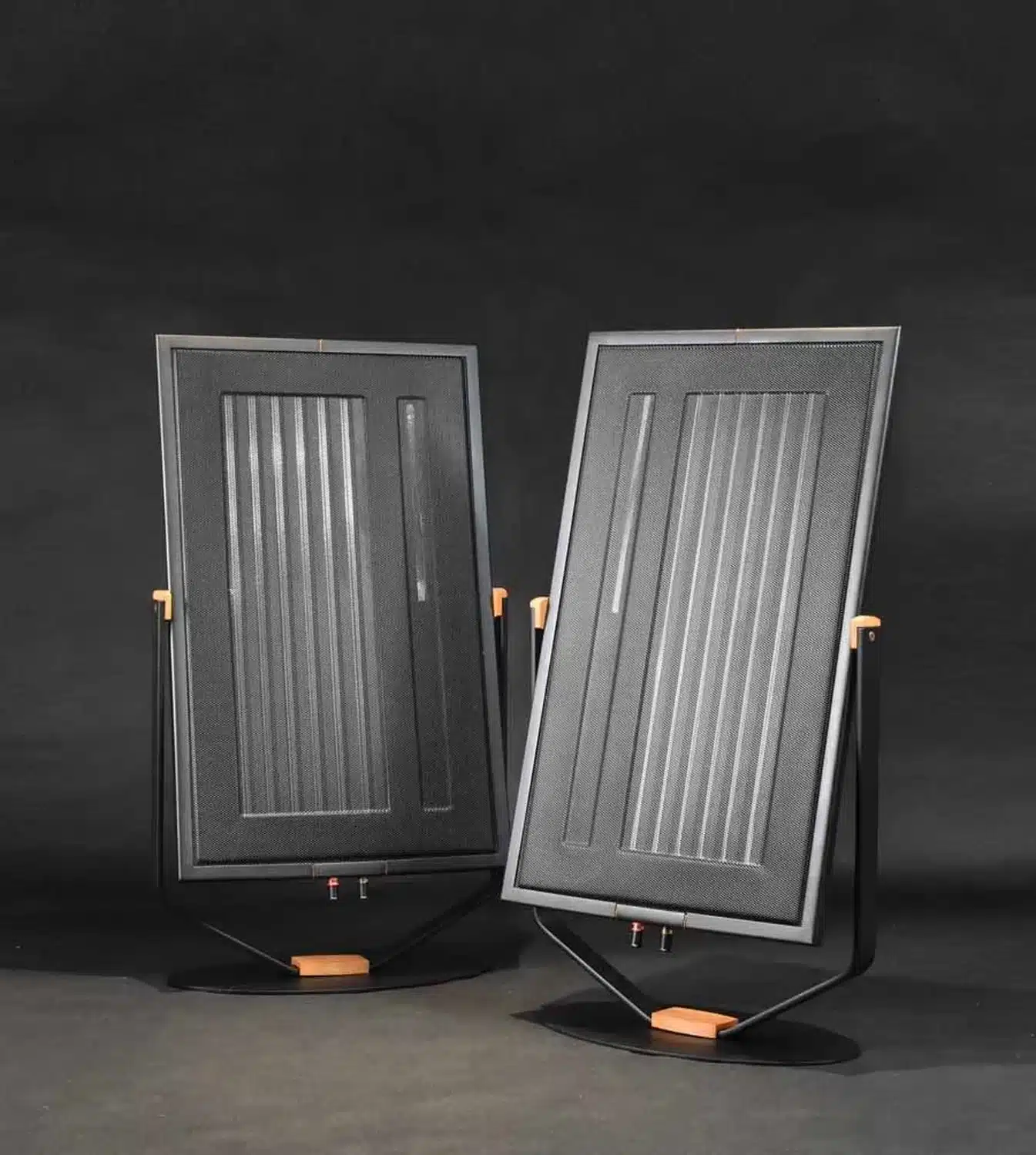 Deux enceintes panneau Diptyque Audio dp77 noires avec supports en bois sur fond sombre et sol béton teinté (par 1877.audio)