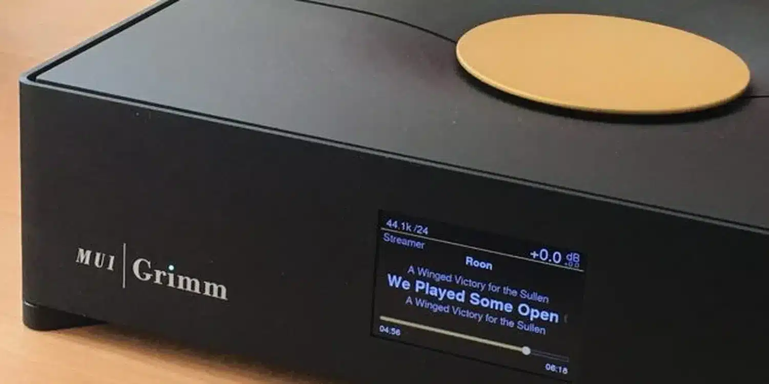 Un DAC Grimm Audio MU1 noir doté d'un écran numérique affichant le morceau actuellement en lecture "We Played Some Open chords" de l'artiste "A Winged Victory for the Sullen" (par 1877.audio)