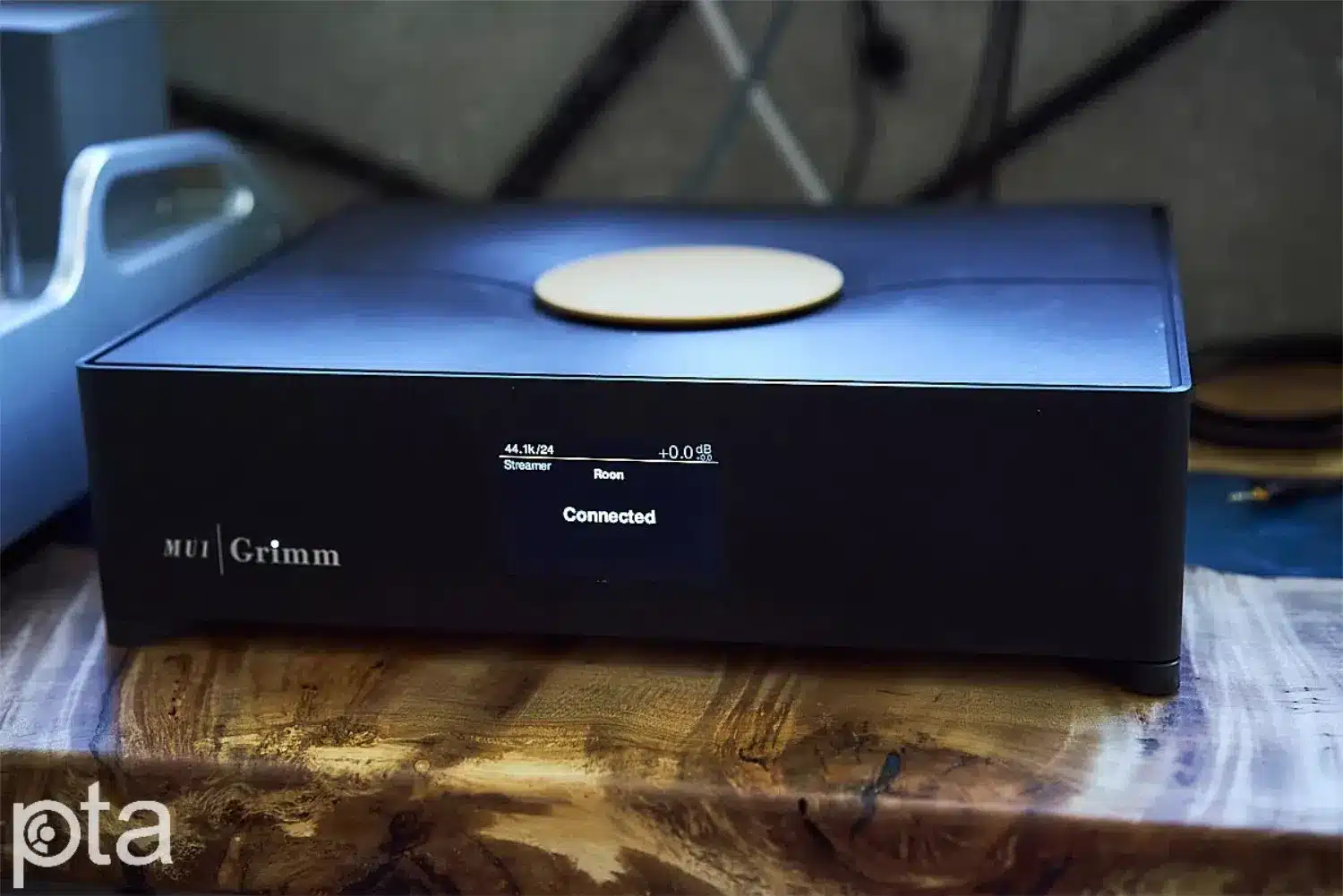 Un appareil de streaming, le Grimm Audio MU1, affichant le statut « Connecté » sur son écran numérique, est posé sur une surface en bois épais et très texturé (par 1877.audio)