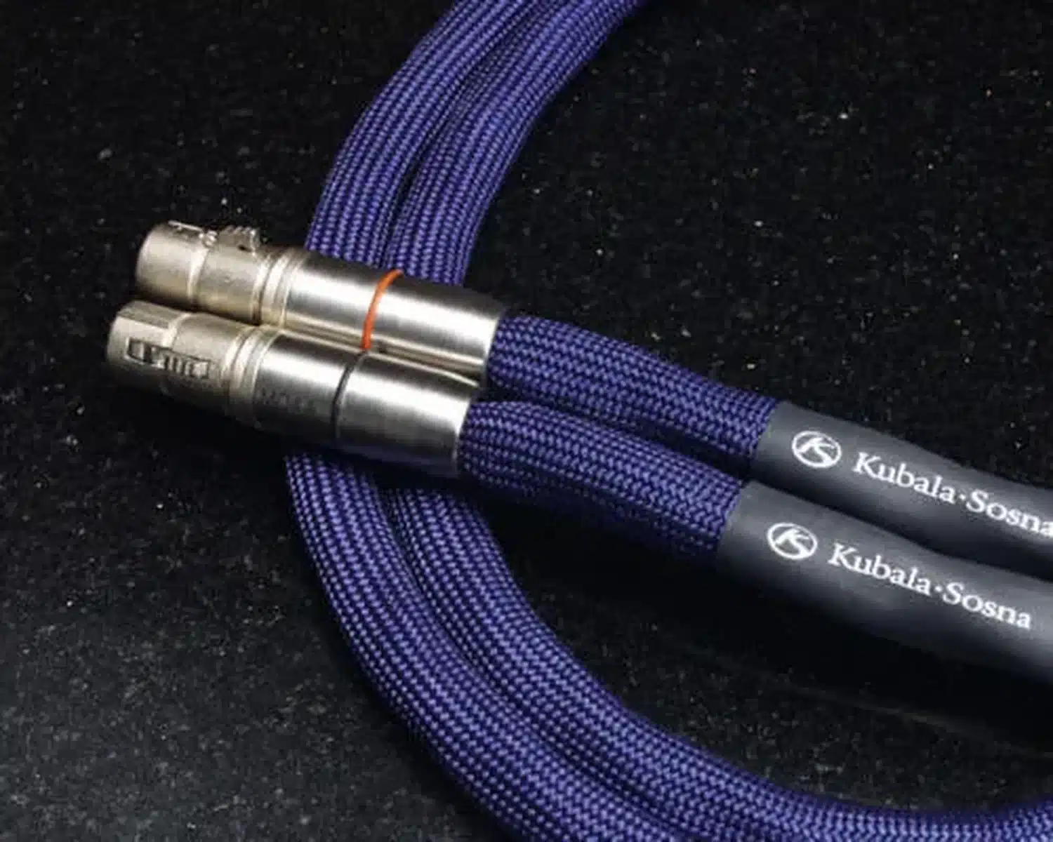 Une paire de câbles audio de modulation haut de gamme Kubala Sosna Emotion avec leurs connecteurs métalliques en XLR et leur gaine en tissu bleu (par 1877.audio)