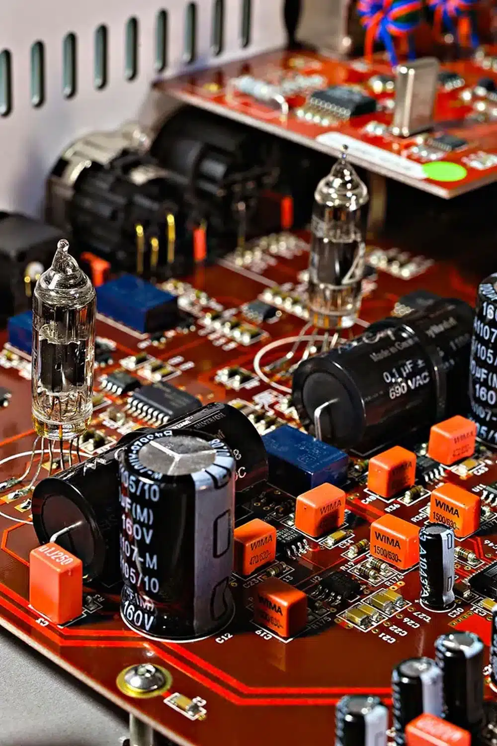 Gros plan d'un circuit imprimé rouge comportant des valves à tube, divers condensateurs et un câblage complexe, mettant en évidence les détails du Vermeer Audio Two (par 1877.audio)